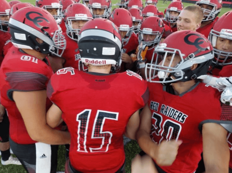 Highschool Red Raiders In a HS Football Team Huddle